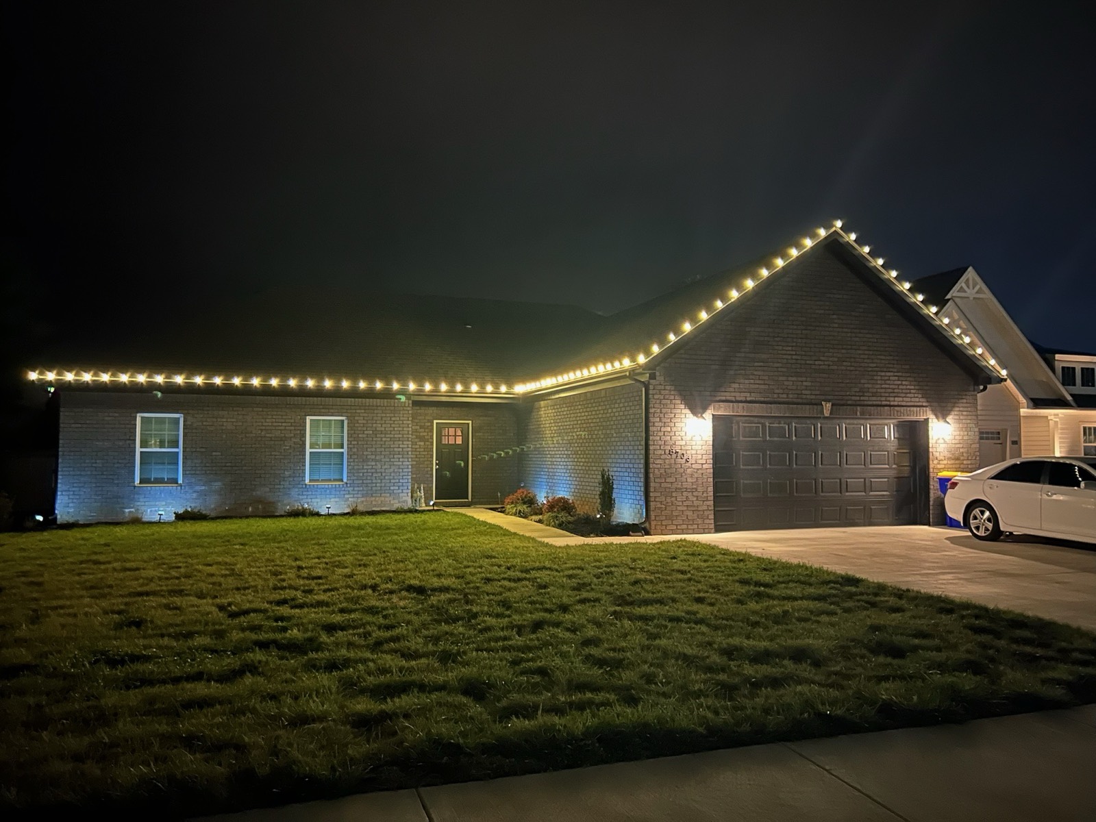 Ranch home with warm white roofline holiday lighting across the full elevation, Bowling Green KY